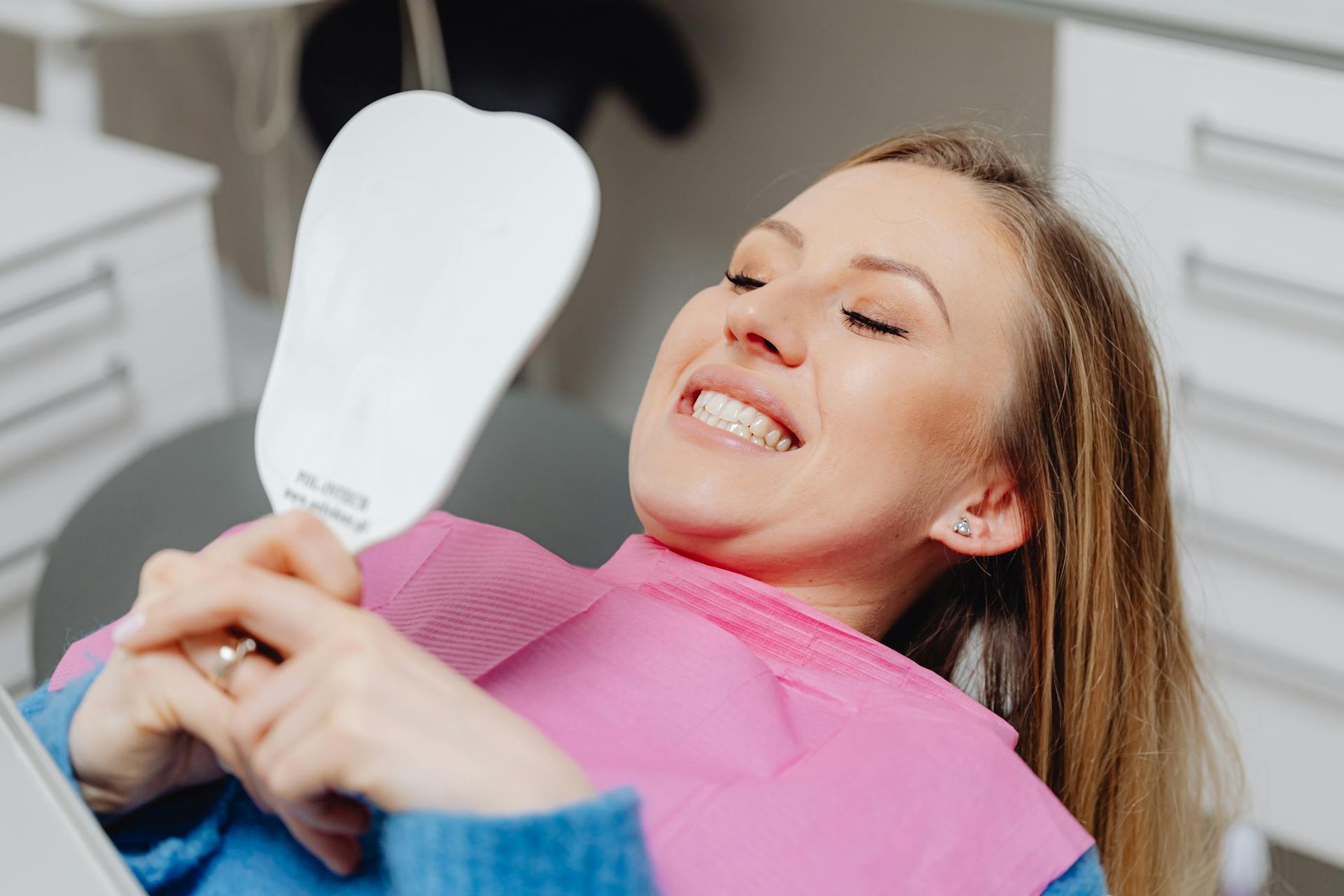 Happy patient admiring her smile at Woodcock Lane Dental Care